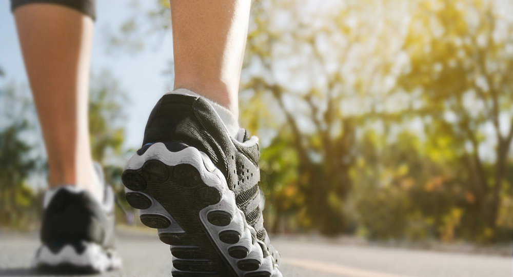 Athlete runner feet running on road closeup on shoe with nature background