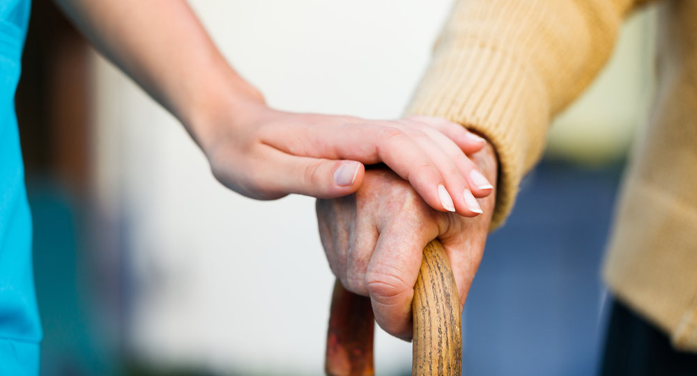 Doctor holding a senior patients 's hand on a walking stick